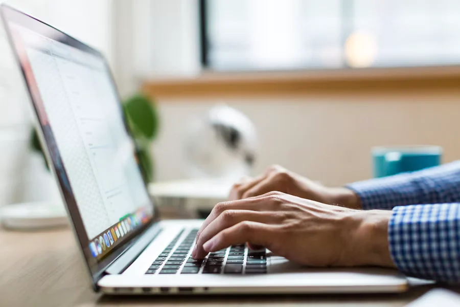 Researcher typing a manuscript on a laptop at a desk