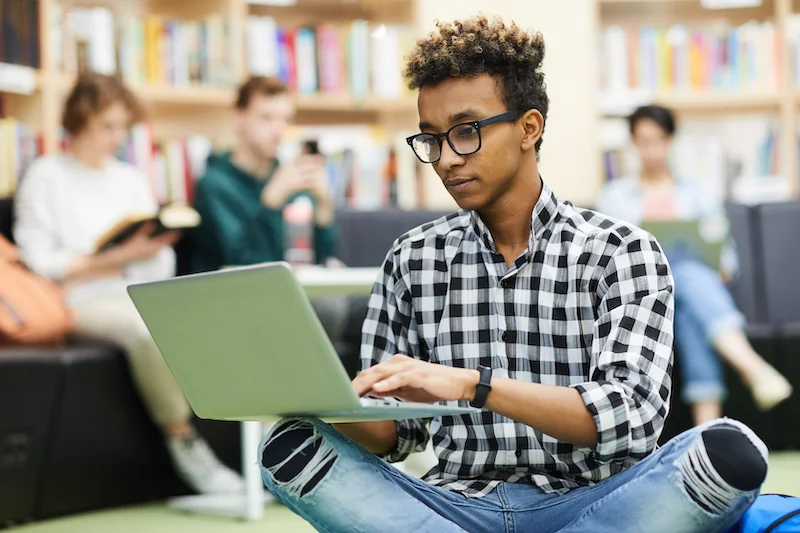 Researcher reviewing an academic manuscript on a laptop in a university library